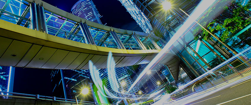 A long exposure photo of a city skyline at night. The long exposure creates light trails from car headlights and streetlights. The image also includes Hong Kong Skywalk: [invalid URL removed] which is a long elevated walkway connecting two skyscrapers.