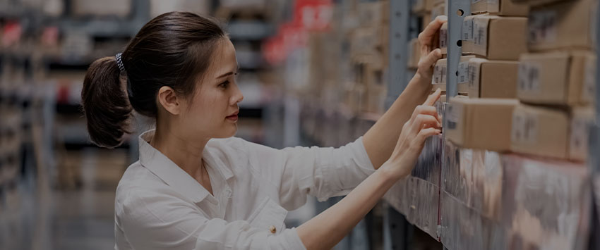 Woman checking boxes in a warehouse rack