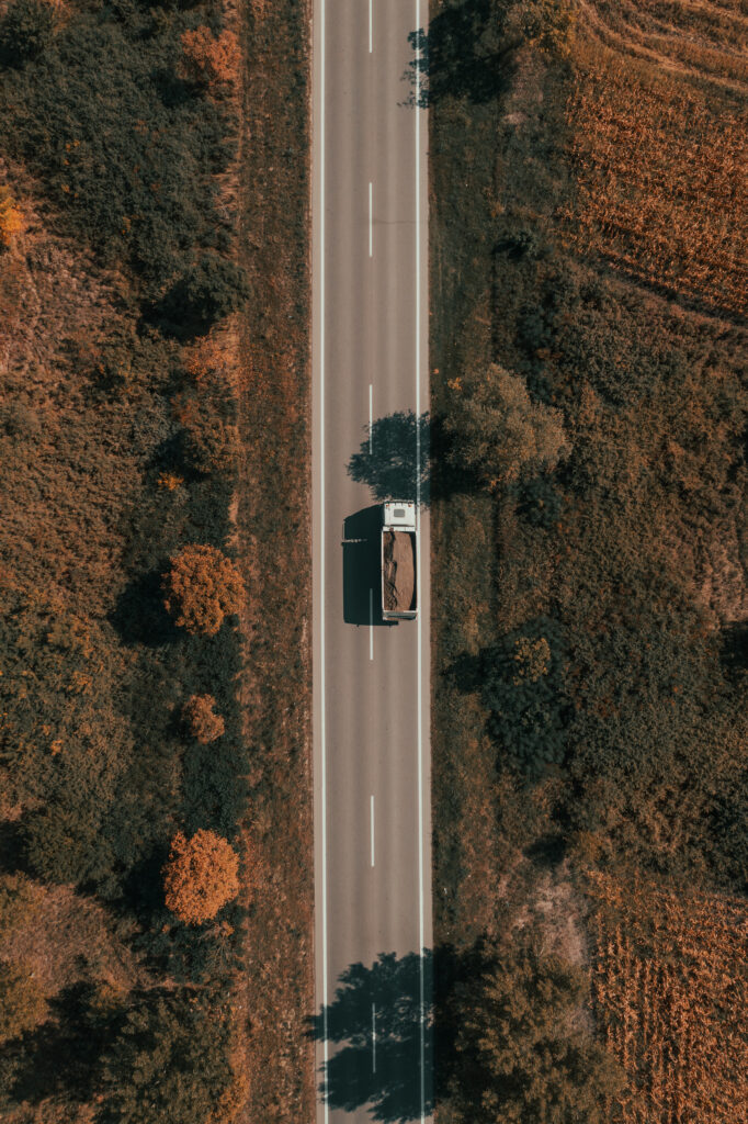 Aerial shot of freight truck transporting sand as construction material, top down drone pov from high angle view