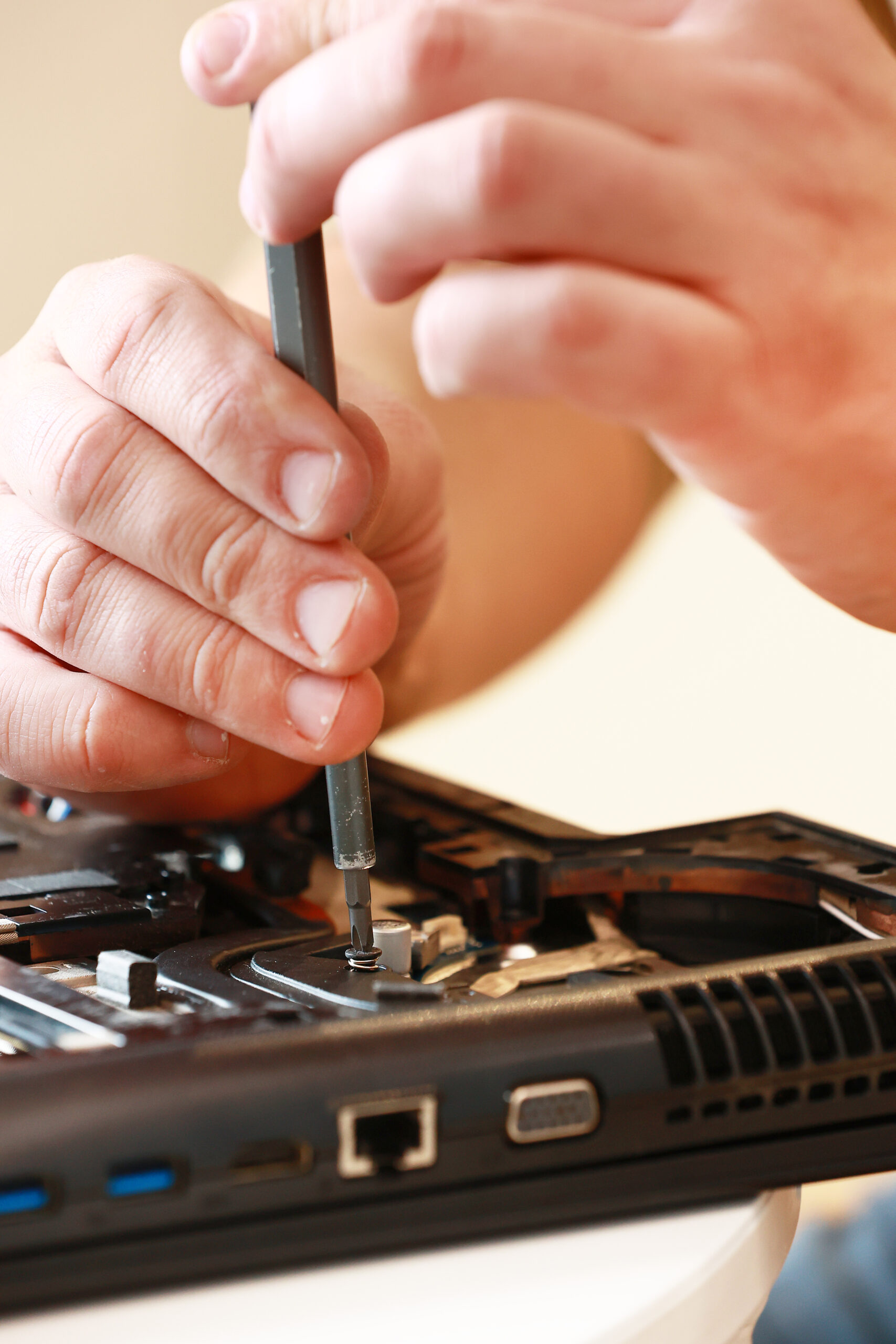Repaiman with screwdriver fixing disassembled laptop parts. Technical support and fixing gadgets problems. Servicing, repairing, cleaning, maintaining computers. Repair shop. Hardware maintenance.