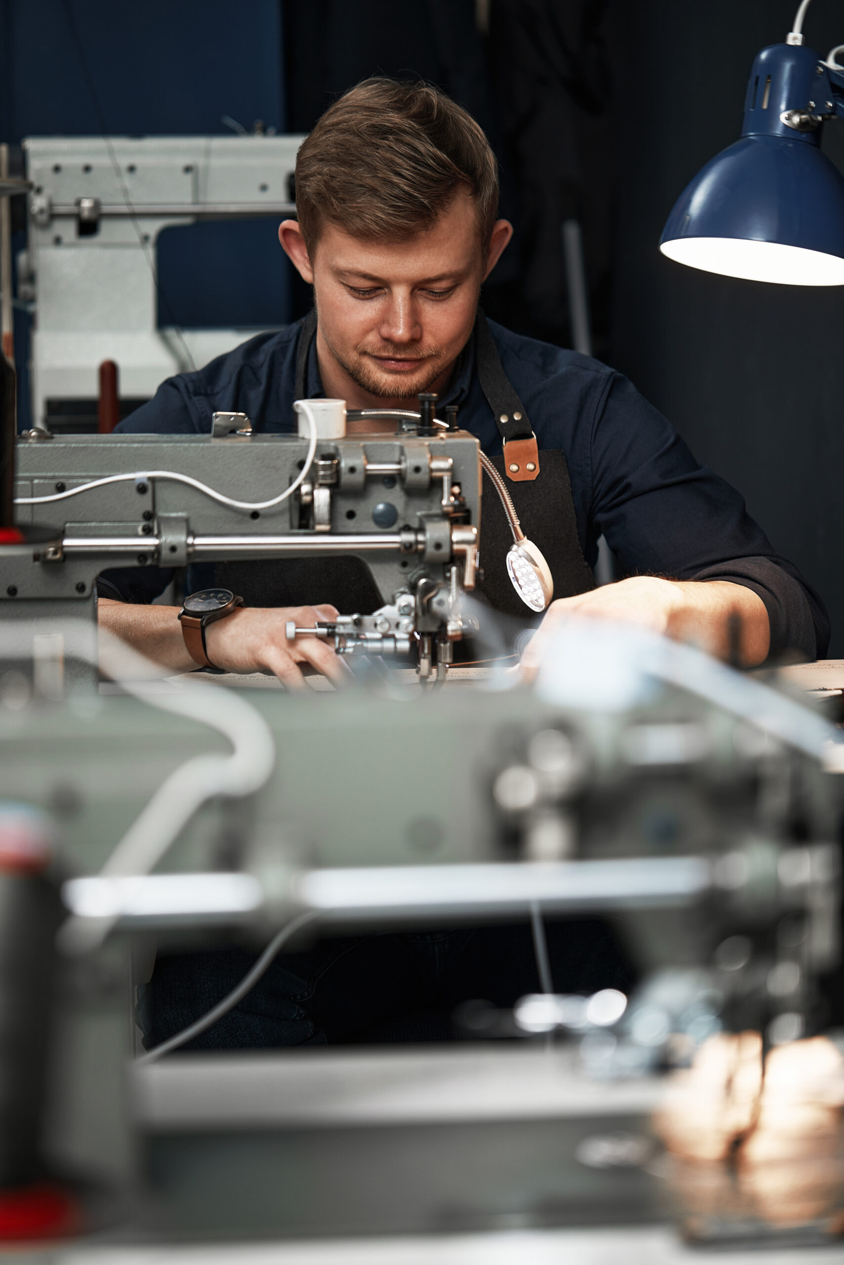 Working process of leather craftsman. Tanner or skinner sews leather on a special sewing machine, close up.worker sewing on the sewing machine.