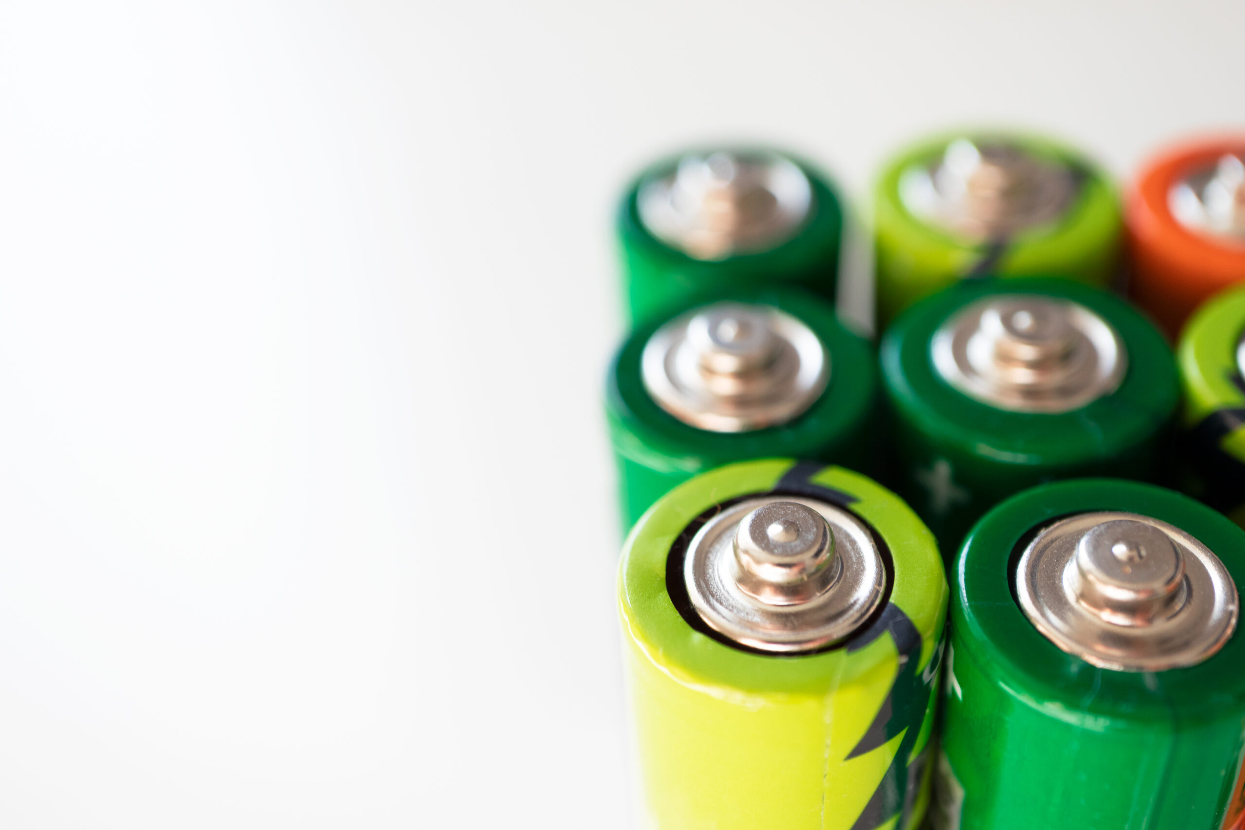 Various alkaline batteries on white background with selective focus. Concept waste sorting and environmental pollution