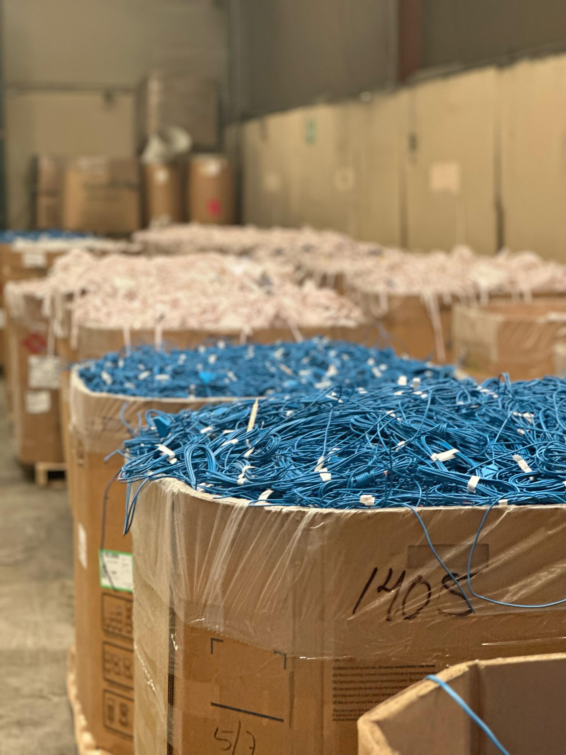 A pile of blue electrical wires in cardboard boxes in a warehouse.